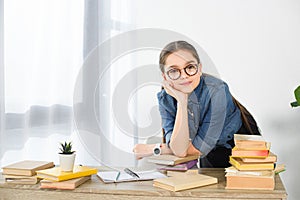 adorable preteen child resting chin on hand at table with books photo