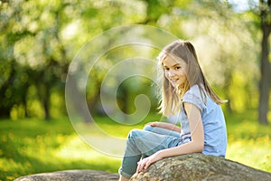 Adorable preteen girl in blooming apple tree garden on beautiful spring day.