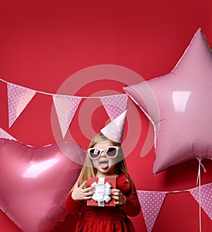 Adorable pretty girl with pink balloons and red present gift and birthday cap