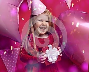 Adorable pretty girl with pink balloons and red present gift and birthday cap