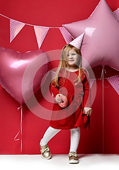 Adorable pretty girl with pink balloons and red present gift and birthday cap