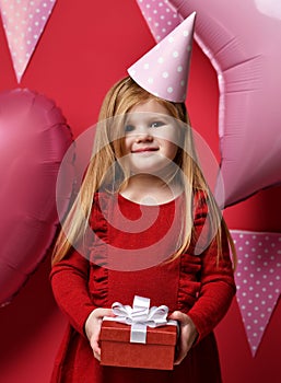 Adorable pretty girl with pink balloons and red present gift and birthday cap