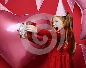 Adorable pretty girl with pink balloons and red present gift and birthday cap