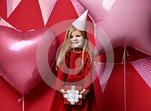 Adorable pretty girl with pink balloons and red present gift and birthday cap