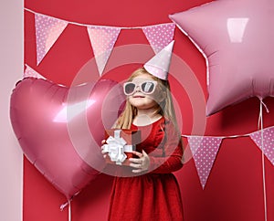 Adorable pretty girl with pink balloons and red present gift and birthday cap