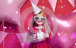 Adorable pretty girl with pink balloons and red present gift and birthday cap
