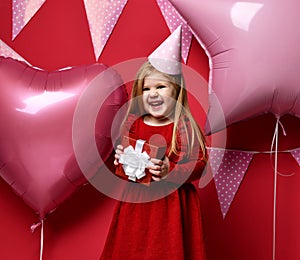 Adorable pretty girl with pink balloons and red present gift and birthday cap