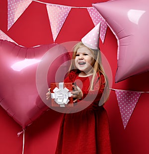 Adorable pretty girl with pink balloons and red present gift and birthday cap