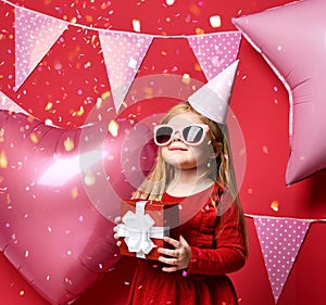 Adorable pretty girl with pink balloons and red present gift and birthday cap