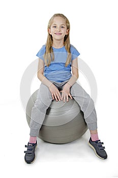 Adorable pretty young girl sitting in Pilates ball.