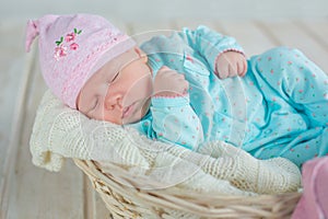Adorable qute baby girl sleeping in white basket on wooden floor