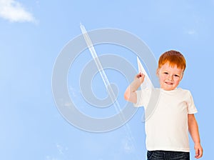 Adorable redheaded boy with paper plane on sky