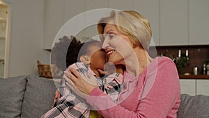 Adorable school age multiracial girl and grandma whispering gossips at home