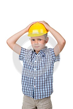 Adorable serious future builder in yellow helmet and blue checkred shirt, isolated on white background