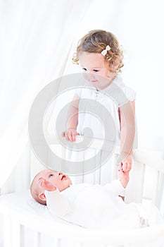Adorable siblings playing in a white sunny bedroom