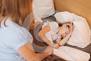 Adorable sick little girl sleeping on bed in children room under blanket at home. Concept of children health.