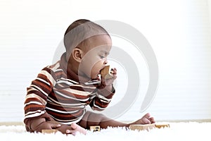 Adorable six month crawling African American baby playing with wooden developmental toys on fluffy white rug, put a toy in the