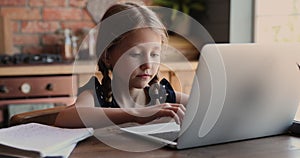 Adorable small 7s child using computer, studying at home.