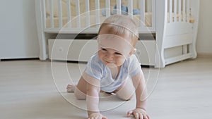 Adorable smiling baby crawling on floor towards the camera