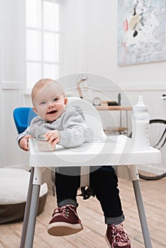 Adorable smiling child sitting in a baby chair in the