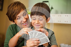 Adorable smiling couple of boy and his grandmother playing cards game