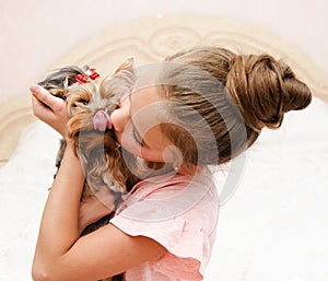 Adorable smiling happy little girl child playing with puppy yorkshire terrier