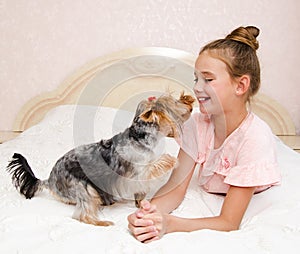 Adorable smiling happy little girl child playing with puppy yorkshire terrier