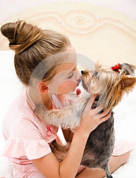 Adorable smiling happy little girl child playing with puppy yorkshire terrier