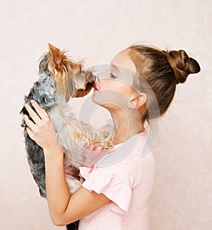 Adorable smiling happy little girl child playing with puppy yorkshire terrier