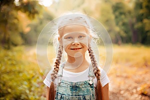 Adorable smiling little blonde girl with braided hair. Cute child having fun on a sunny summer day outdoor.