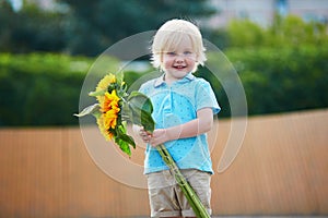 Little boy with bunch of sunflowers outdoors