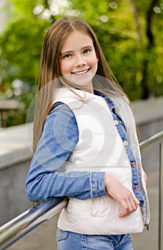 Adorable smiling little girl child preteen standing in the park outdoors