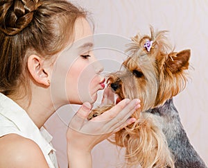 Adorable smiling little girl child schoolgirl holding and playing with pet dog