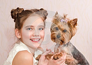 Adorable smiling little girl child schoolgirl holding and playing with pet dog