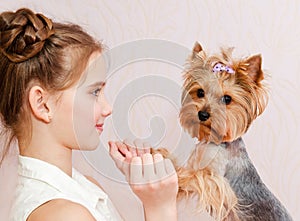 Smiling little girl child schoolgirl holding and playing with pet dog yorkshire terrier