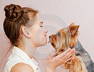 Smiling little girl child schoolgirl holding and playing with pet dog yorkshire terrier