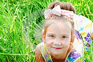 Adorable smiling little girl lying on the grass in summer day