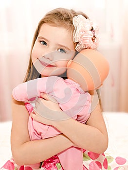 Adorable smiling little girl playing with a doll