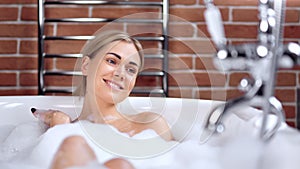 Adorable smiling sensual young woman flirting and relaxing taking bath with foam medium close-up