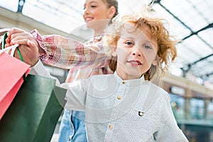 Adorable smiling siblings holding shopping bags together