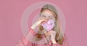 Adorable smiling young girl taking on her face mask against viruses. Slow motion video