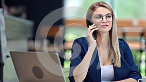 Adorable stylish businesswoman talking using smartphone having positive emotion at modern office