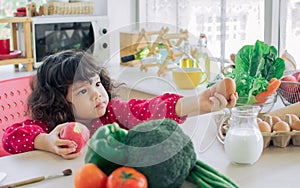 Adorable sweet caucasian little kid girl standing in kitchen at home, cooking, playing and smiling with happiness, holding, eating