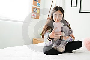 Adorable teen girl texting on her phone while in her bedroom