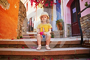 Adorable three years old girl sitting on a street of beautiful Mediterranean town Collioure in France