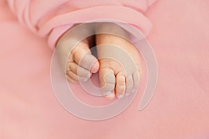 Adorable tine baby girl feet on soft pink background, maternity and babyhood concept