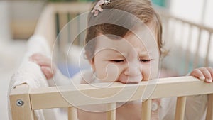 Adorable toddler bitting cradle at bedroom