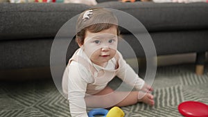 Adorable toddler bitting plastic hoop sitting on floor at home