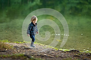 Adorable toddler boy admiring the Balsys lake, one of six Green Lakes, located in Verkiai Regional Park. Child exploring nature on