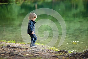 Adorable toddler boy admiring the Balsys lake, one of six Green Lakes, located in Verkiai Regional Park. Child exploring nature on